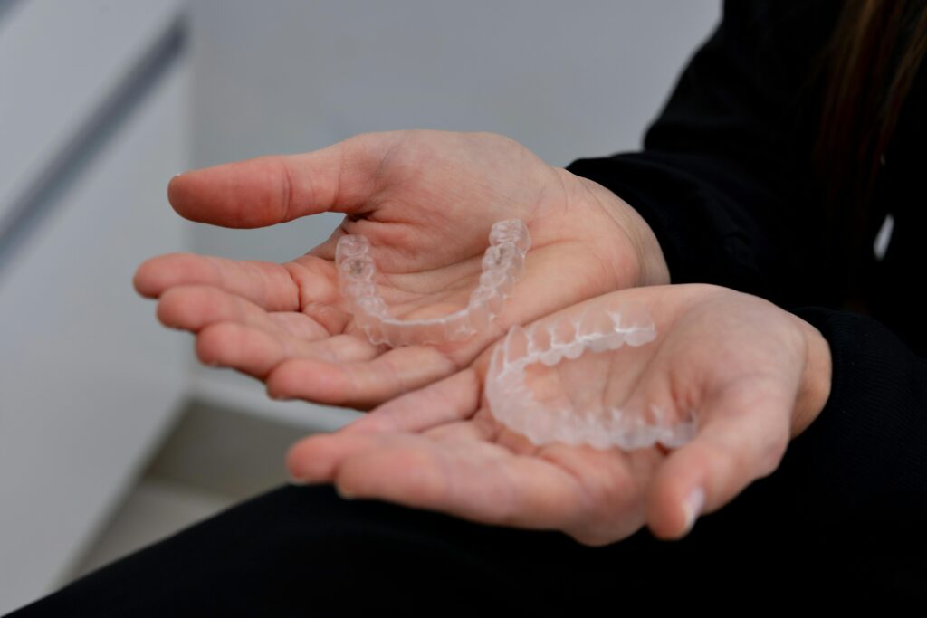 Hands holding clear aligner trays used in SureSmile® and Invisalign® treatment at Digital Smiles.