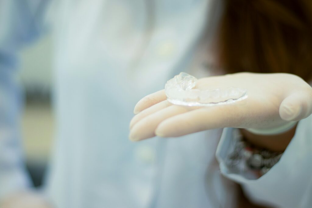 Dentist in gloves holding a clear aligner tray for orthodontic treatment with SureSmile® and Invisalign® at Digital Smiles.